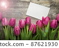 Pink Tulips and gift card on a wooden background. Space for the text. Top view 87621930