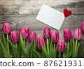 Pink Tulips and gift card on a wooden background. Space for the text. Top view 87621931