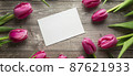 Pink Tulips and gift card on a wooden background. Space for the text. Top view 87621933