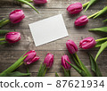 Pink Tulips and gift card on a wooden background. Space for the text. Top view 87621934