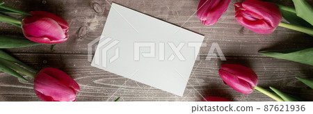 Pink Tulips and gift card on a wooden background. Space for the text. Top view 87621936