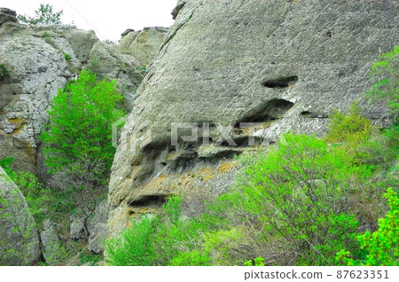 Horizontal background with a magnificent landscape of the Crimean Peninsula. Top view of the mountains covered with lush greenery and the thick clouds below the peaks. Clear blue sky. Copy space. 87623351