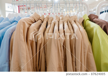 Clothes on hangers in a retail shop. Shirts and clothes for women, man and children on racks in a Clothes on hangers in a retail shop. Shirts and clothes for women, man and children on racks in a 87624005