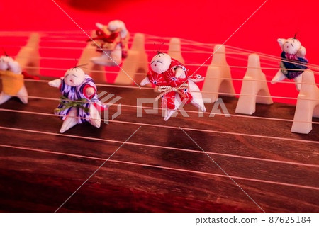 A small cute Japanese doll and a kin are placed on the red felt. 87625184