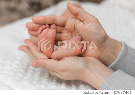 dad holds the baby's legs in his hands. The concept of a happy family. close-up dad holds the baby's legs in his hands. The concept of a happy family. close-up 87627461