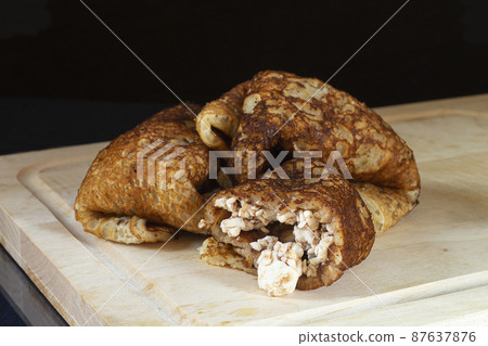 Pancakes with stuffing in white plate on table with reflection Pancakes with stuffing in white plate on table with reflection 87637876