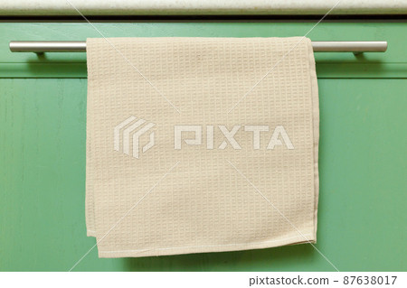Waffle kitchen towel hanging on the doorknob of a home kitchen cabinet Waffle kitchen towel hanging on the doorknob of a home kitchen cabinet 87638017