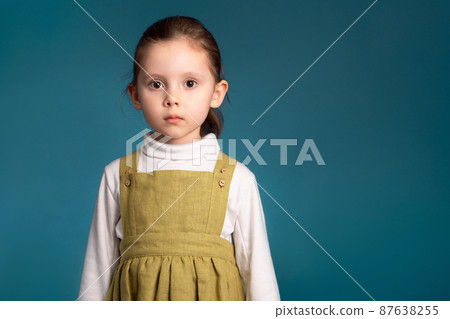 Cropped studio simple portrait of little kid girl 5 y.o. looking at camera over blue background Cropped studio simple portrait of little kid girl 5 y.o. looking at camera over blue background 87638255