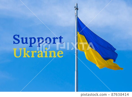 SUPPORT UKRAINE text on Ukrainian national flag flutters in the wind against the blue sky. National symbol of ukrainian people - blue and yellow. No war. War Protest against Russian invasion of 87638414