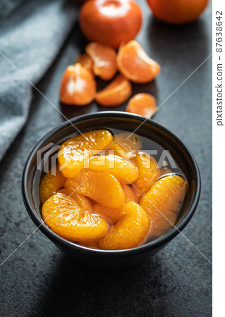 Canned tangerine. Pickled mandarin fruit in bowl on black table. 87638642