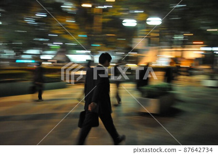 A man on the way home from work walking quickly at night in Shinjuku 87642734