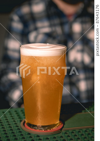 Closeup of frothy wheat unfiltered beer in glass on bar counter 87643176