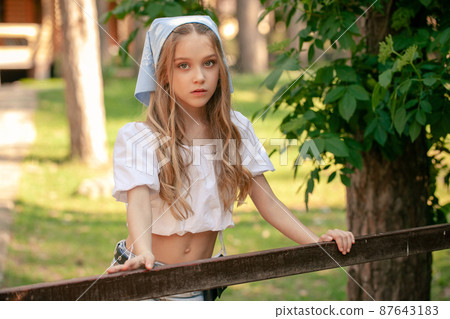 Pretty teenage girl posing near fencing in summer country estate Pretty teenage girl posing near fencing in summer country estate 87643183
