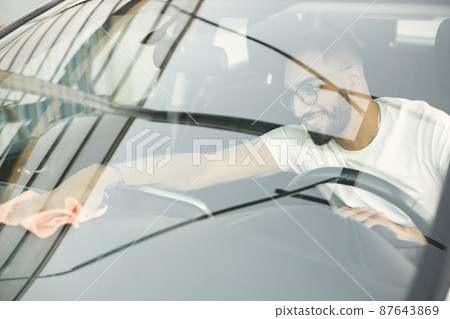 Indian man polishing inside his white car with a rug Indian man polishing inside his white car with a rug 87643869
