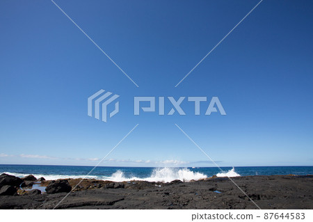 A distant view of the waves and horizon of the Pacific Ocean hitting the black reefs of Kona on the Big Island of Hawaii A distant view of the waves and horizon of the Pacific Ocean hitting the black reefs of Kona on the Big Island of Hawaii 87644583