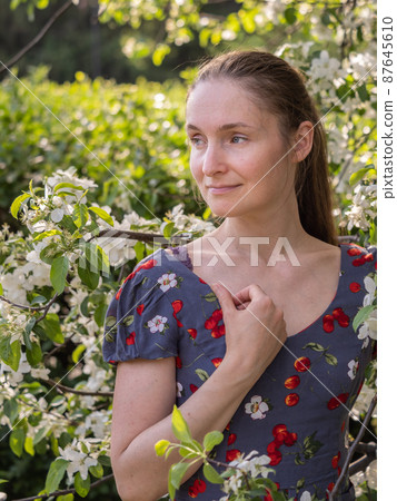 Beautiful Young woman without makeup in a spring park among flowering trees 87645610