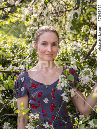 Beautiful Young woman without makeup in a spring park among flowering trees Beautiful Young woman without makeup in a spring park among flowering trees 87645611