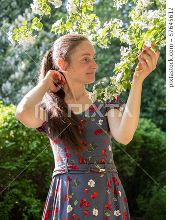 Beautiful Young woman without makeup in a spring park among flowering trees Beautiful Young woman without makeup in a spring park among flowering trees 87645612