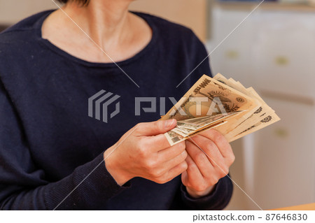 A woman counting money to make ends meet A woman counting money to make ends meet 87646830