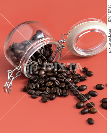 Roasted Coffee beans in a glass jar on pink background close up 87648753