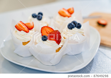 close-up. cupcakes are decorated with white cream and fresh berries close-up. cupcakes are decorated with white cream and fresh berries 87649298