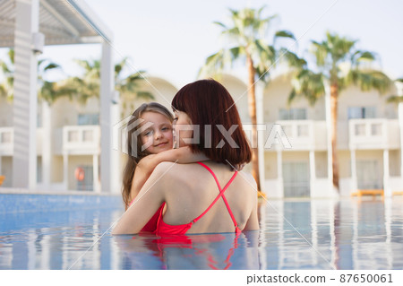Happy caucasian mother and her little cute daughter playing in swimming pool. 87650061