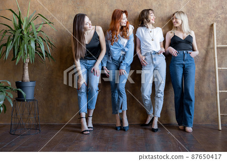 Portrait of four diverse girlfriends standing together on the wall background indoors Portrait of four diverse girlfriends standing together on the wall background indoors 87650417