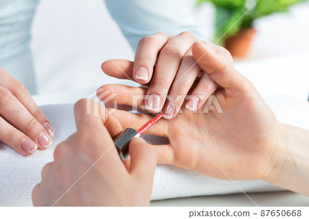 Manicurist working with client's nails at table Manicurist working with client's nails at table 87650668