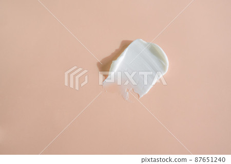 White smear of cosmetic cream on a beige background. White smear of cosmetic cream on a beige background. 87651240