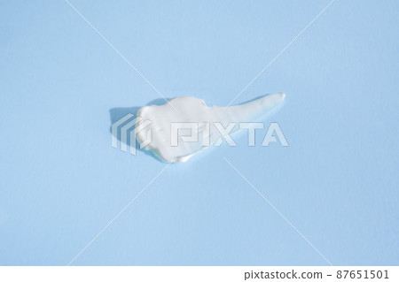 White smear of cosmetic cream on a blue background.  87651501