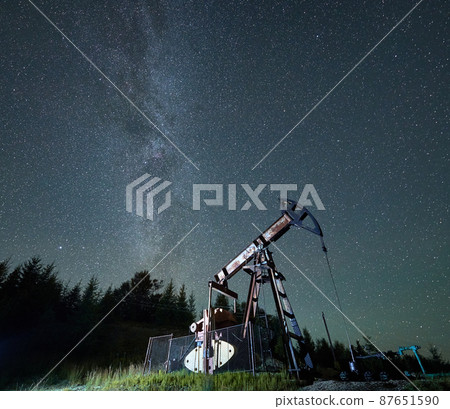 Beautiful view of petroleum pump jack under night sky with stars. Magnificent scenery of night oil field with oil pump rocker-machine. Concept of petroleum industry and oil extraction. Beautiful view of petroleum pump jack under night sky with stars. Magnificent scenery of night oil field with oil pump rocker-machine. Concept of petroleum industry and oil extraction. 87651590
