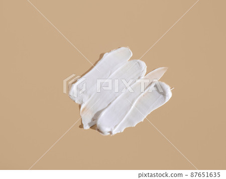 White smear of cosmetic cream on a beige background.  87651635