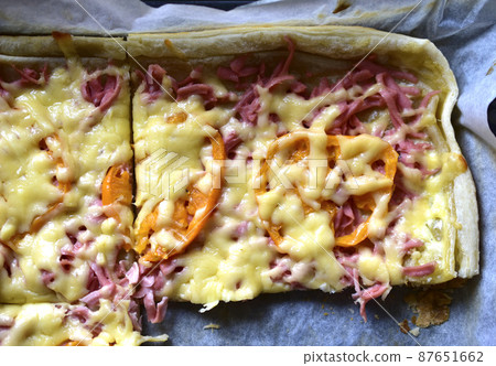 Homemade pizza with meat and yellow tomatoes on a baking sheet Homemade pizza with meat and yellow tomatoes on a baking sheet 87651662