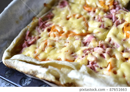 Homemade pizza with meat and yellow tomatoes on a baking sheet Homemade pizza with meat and yellow tomatoes on a baking sheet 87651663