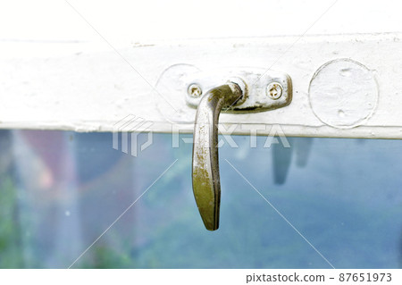 Old steel handle on the window pane of the old window Old steel handle on the window pane of the old window 87651973