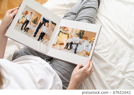 top view woman holds photobook in hands while sitting in bed.family photo shoot top view woman holds photobook in hands while sitting in bed.family photo shoot 87652842