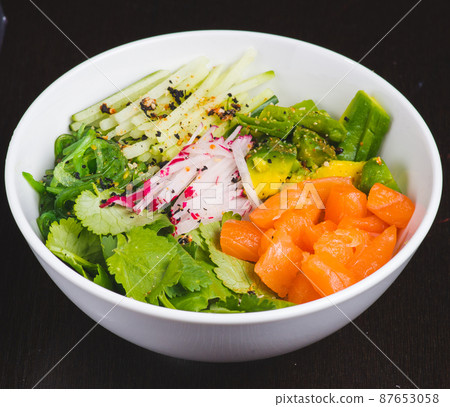 Salmon Salad with spinach, cherry tomatoes, corn salad, baby spinach, fresh mint and basil. Home made food. Concept for a tasty and healthy meal. Dark stone background. Top view. Close up. 87653058