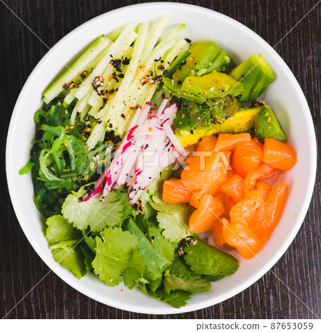 Salmon Salad with spinach, cherry tomatoes, corn salad, baby spinach, fresh mint and basil. Home made food. Concept for a tasty and healthy meal. Dark stone background. Top view. Close up. 87653059