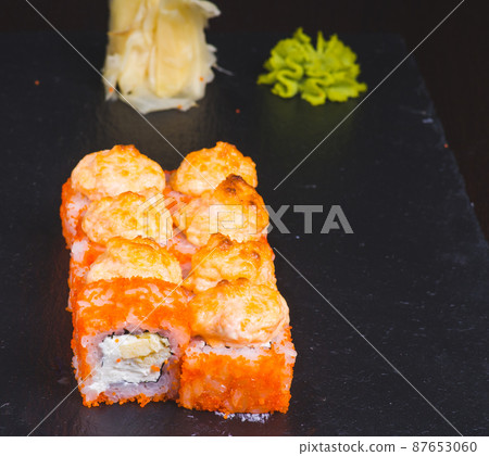Sushi rolls california with snow crab, cream cheese, cucumber, sesame seeds and masago caviar on black background with reflection. Sushi menu, japanese kitchen. 87653060