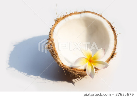 Half coconut with plumeria flower 87653679
