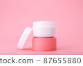 Opened cosmetic jar on pink pedestal against bright pink background. Concept of luxury repairing nourishing cream  87655880
