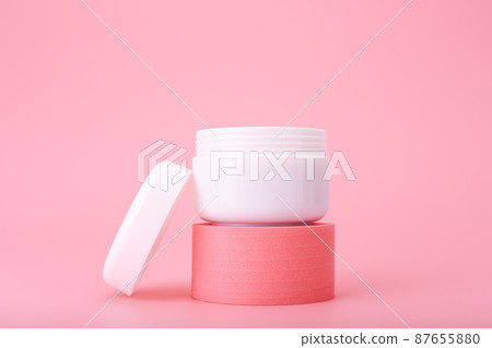 Opened cosmetic jar on pink pedestal against bright pink background. Concept of luxury repairing nourishing cream  87655880
