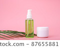 Green cleaning gel for face and cosmetic jar with cream or mask on pink background with palm leaf 87655881