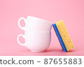 Creative, minimal dishwashing concept, yellow cleaning sponge next to two white ceramic cups on pink background 87655883