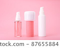 Set of beauty products in a row on white table against pink background. Face cleansing foam, cream and lotion 87655884