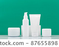 Set of cosmetic products for daily skincare in a row on white table against green background 87655898
