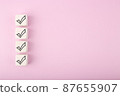 Four black checkmarks on white toy cubes in a row against bright pastel purple background with copy space 87655907
