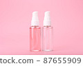 Two different face lotion, liquid foam or gel for skin cleaning in transparent tubes on bright pink background 87655909
