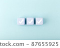 Three white checkmarks on blue toy cubes in a row on bright pastel blue background with copy space 87655925