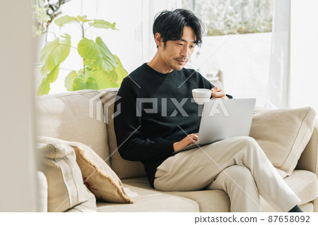 Middle man teleworking on the sofa at home 87658092